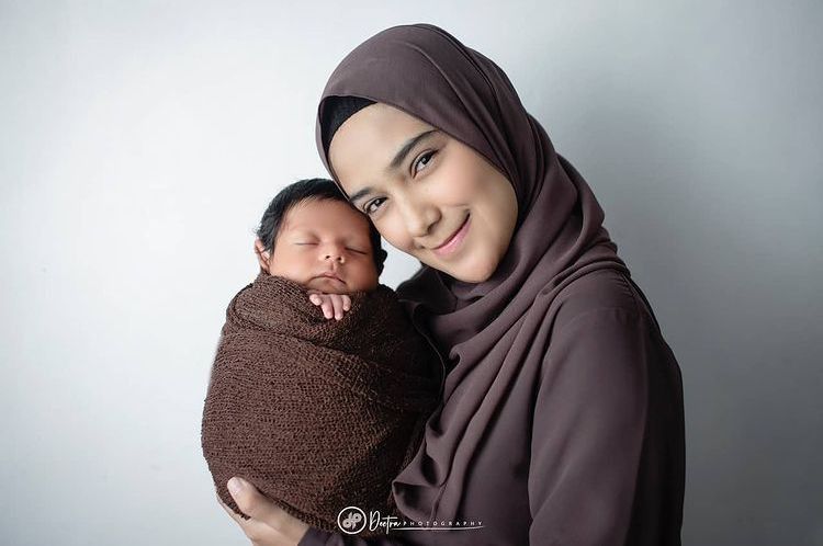 1. Baby Baihaqqi dan Nadya Mustika kompak mengenakan swaddle dan outfit senada berwarna coklat.
